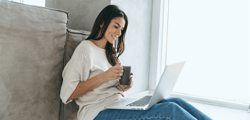 woman using laptop drinking coffee